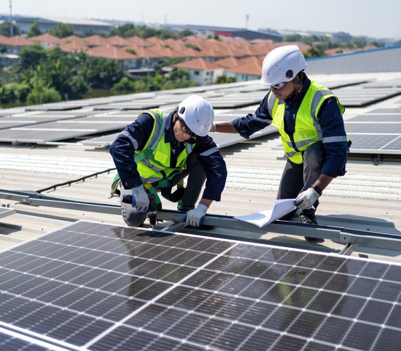 engineer-on-rooftop-kneeling-next-to-solar-panels-photo-voltaic-check-drawing-for-good-installation.jpg